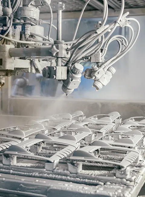 Industrial robot automatically paints multiple plastic parts in a manufacturing plant using spray technology.