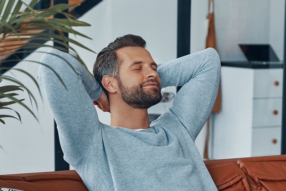 A man relaxes on a couch enjoying high audio quality with a TechniSat radio and Spotify Connect.