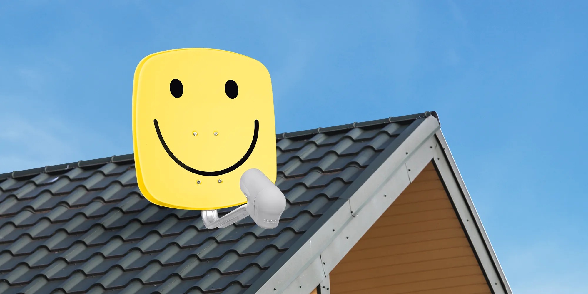 Gelbe Satellitenschüssel mit fröhlichem Smiley-Motiv auf einem Hausdach, vor strahlend blauem Himmel – TV-Empfang mit guter Laune.