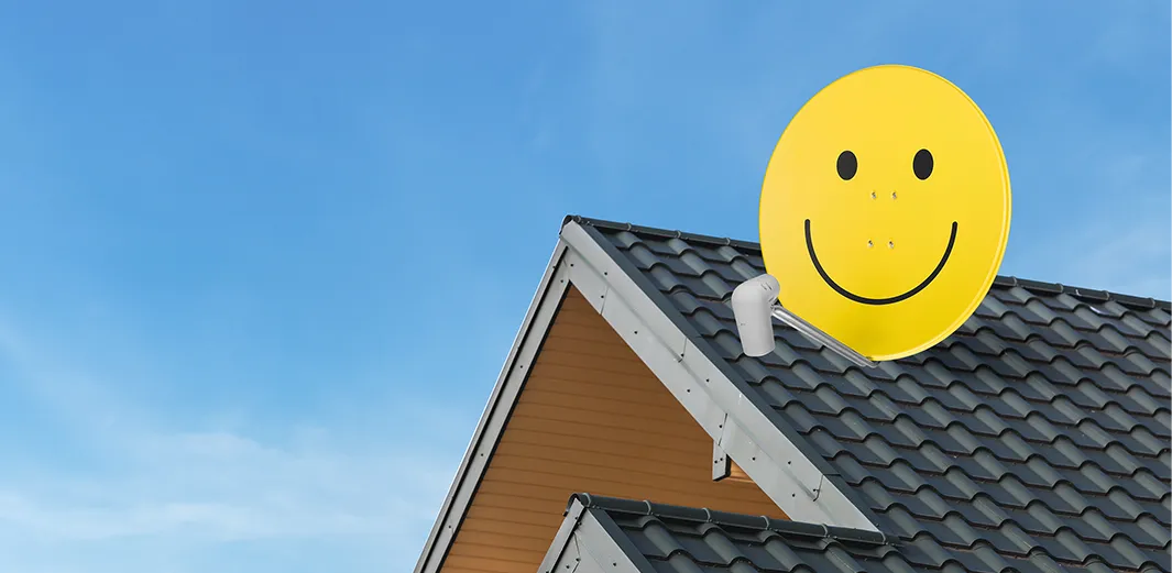 A TechniSat satellite dish with the iconic yellow smiley face on a rooftop enables TV reception.