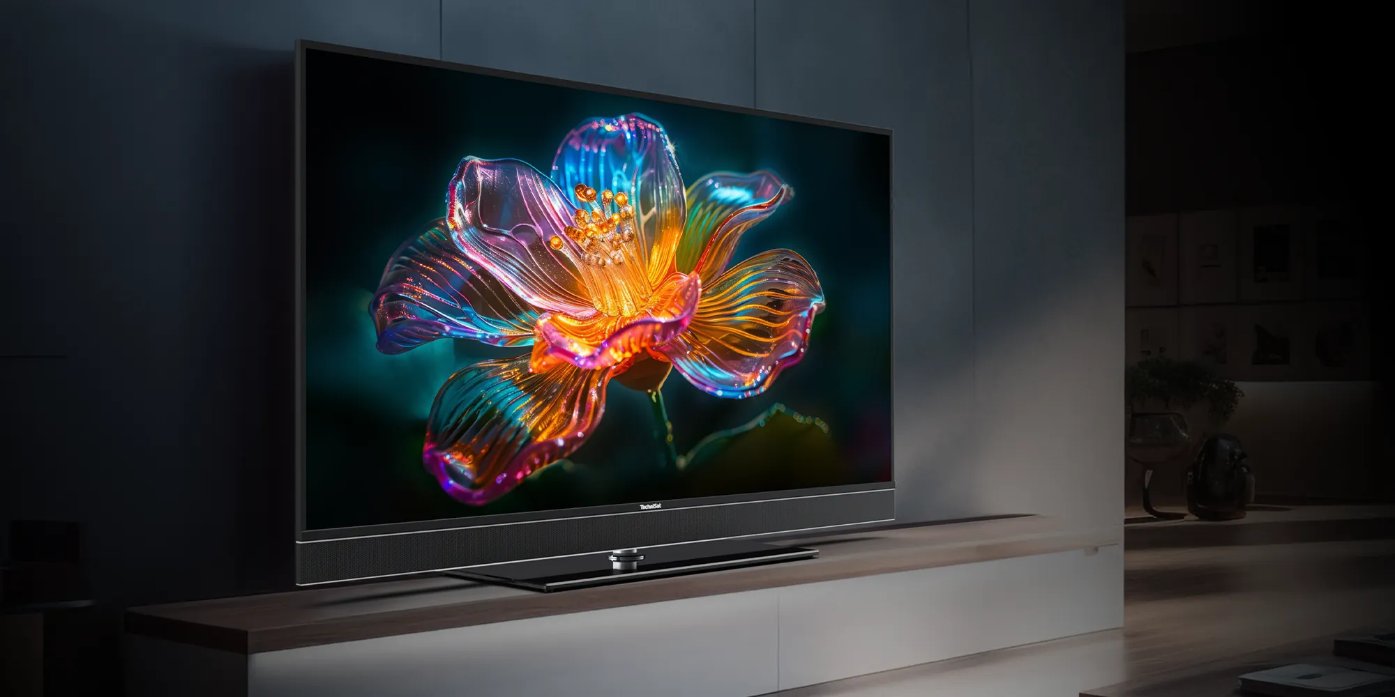 A UHD smart TV from TechniSat sits on a shelf in the living room, displaying a detailed, colorful flower on the screen.