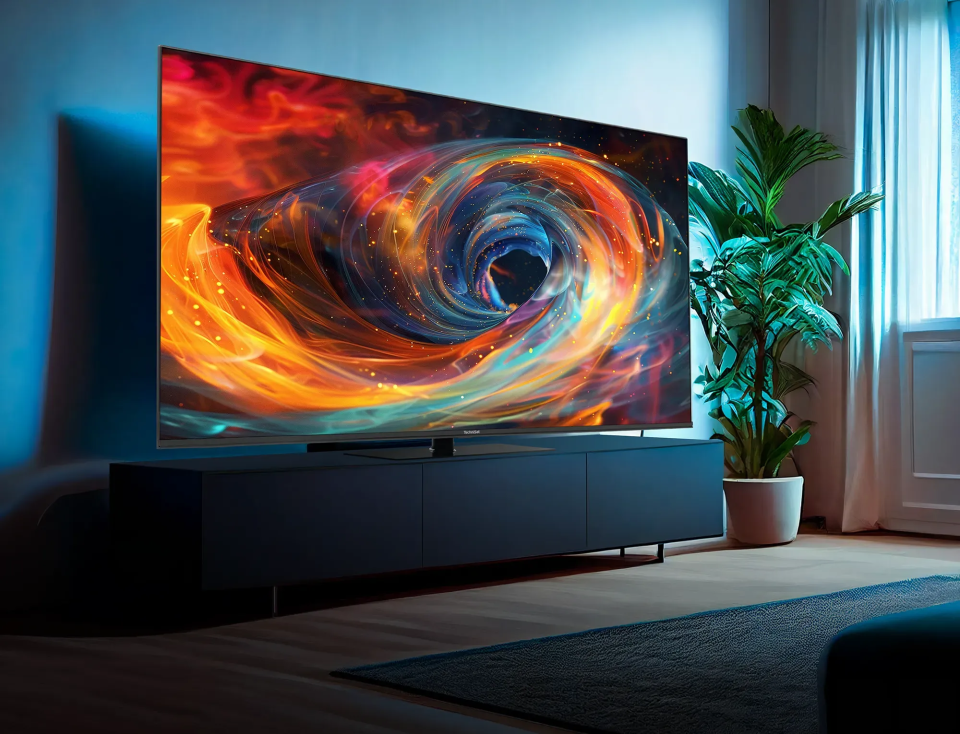Ein TechniSat Fernseher, der ein Universum in leuchtenden Farben zeigt, stehend auf einem Sideboard in einem farblich dunkel gehaltenen Wohnzimmer.